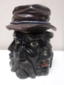 A Victorian lidded tobacco jar in the form of a head with six faces wearing a hat