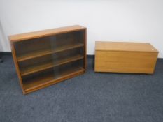 A mid 20th century teak sliding glass door bookcase together with a teak blanket box