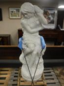 A contemporary carved solid white marble statue of a semi-nude female seated on a rock,
