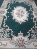 A floral woollen carpet on green ground and a similar rug