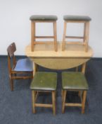 A drop leaf kitchen table together with four mid 20th century leather topped stools and a kitchen
