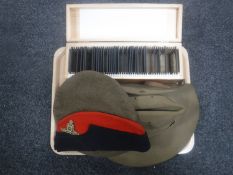 A pine slide box containing vintage glass negatives and three military hats bearing badges