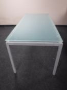 A contemporary glass topped dining table on metal base