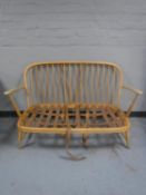 An Ercol two seater settee (no cushions) CONDITION REPORT: Slight wobble in the