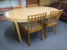 An oval pine effect dining table with two leaves together with a set of four chairs