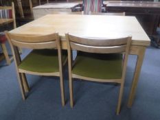 A mid 20th century pull out dining table together with four chairs