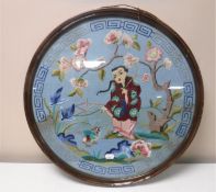 A circular mahogany framed oriental needlework panel