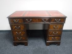 A mahogany twin pedestal writing desk with three leather tooled inset panels