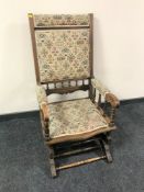 An Edwardian oak framed tapestry upholstered rocking chair