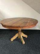 A circular mango wood pedestal dining table