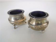 A pair of sterling silver salts with blue glass liners
