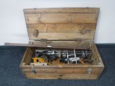 A pine crate containing vintage woodworking tools including planes, hand saw,