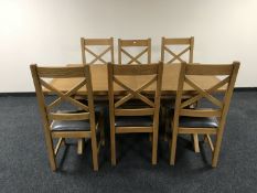 An oak extending dining table on X-frame support and six high backed dining chairs