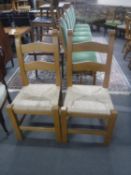 A pair of pine rush seated ladder back kitchen chairs