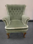 A mid 20th century armchair upholstered in a green buttoned dralon