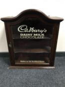 A mahogany arched topped wall cabinet bearing "Cadburys Dairy Milk Chocolate" advertising