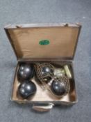 A vintage leather case of four wooden lawn bowls