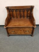 A Gothic carved oak hall settle fitted a drawer,