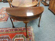 An Edwardian mahogany turnover top D-shaped table on claw and ball feet,