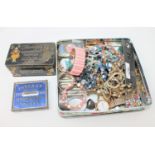 A tin containing two silver napkin rings, costume jewellery, cigarette case, trinket boxes,