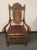 A continental heavily carved beech armchair with brown leather seat,