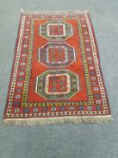 A Caucasian design rug on red ground,