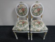 A pair of white and gilt chairs upholstered in a floral fabric