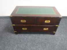 A campaign style three drawer chest with brass mounts and leather inset panel
