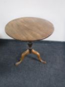 An antique mahogany tilt top pedestal wine table