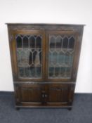 A carved oak leaded glass door bookcase fitted a cupboard beneath