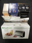 A food saver with bags, box of pressure cooker, stainless steel pans, kitchen utensils,