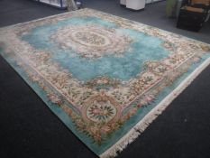 A Chinese fringed embossed carpet on green ground,