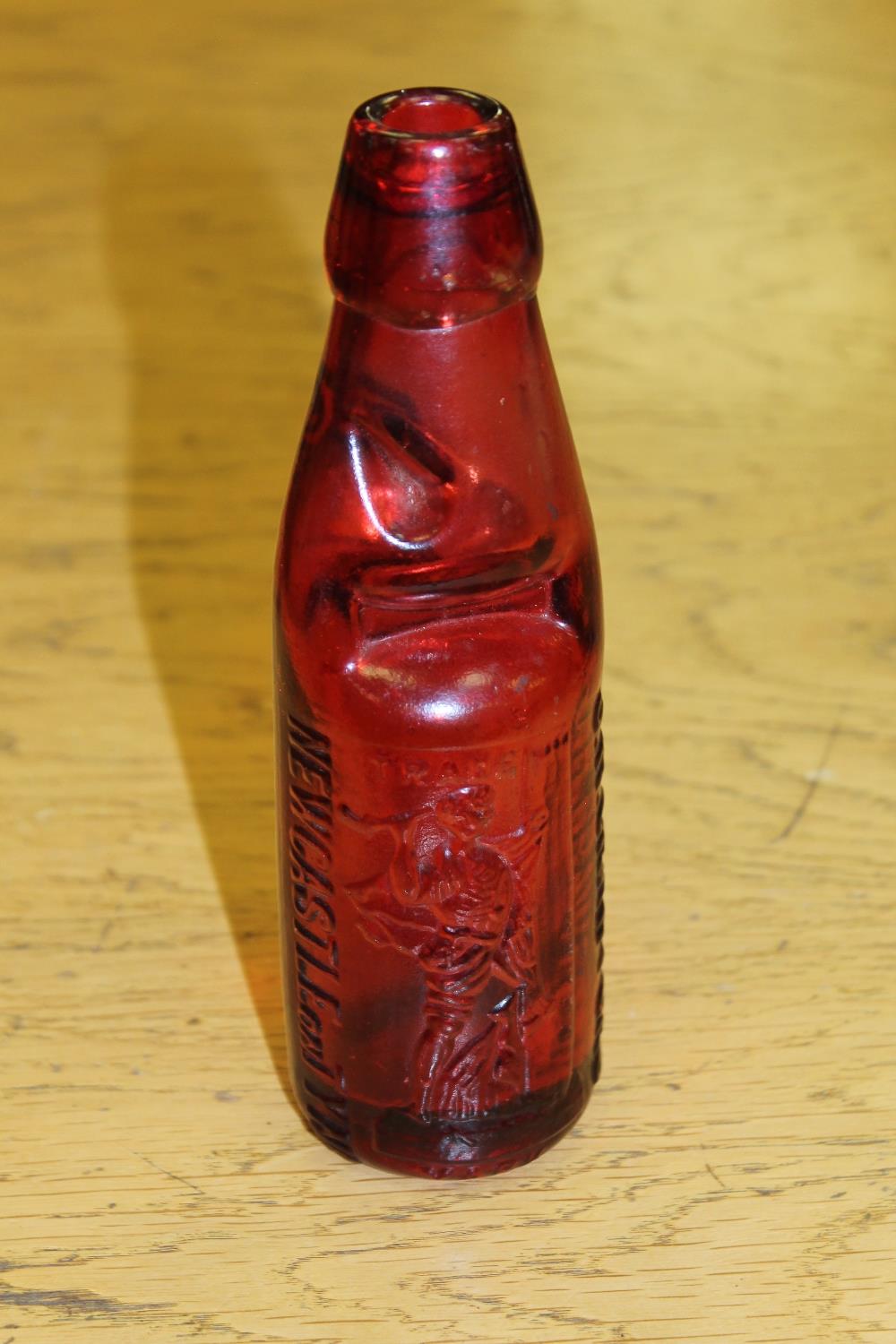 A scarce red glass Codd bottle, with raised trademark J. H.