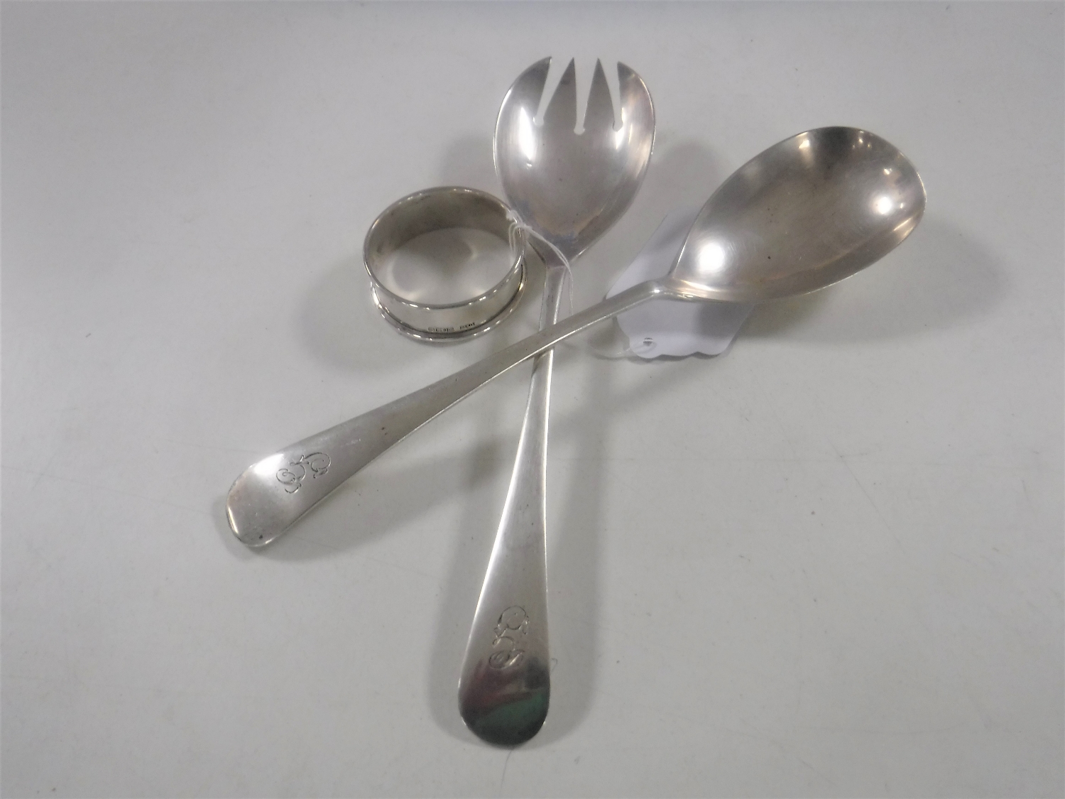 A pair of silver servers together with a silver napkin ring