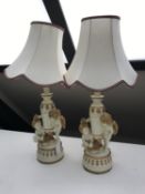A pair of cream and gilt chalk figural table lamps decorated with cherubs