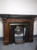 A cast iron Victorian style fire insert in carved pine surround