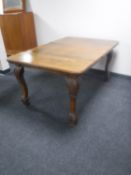 An Edwardian oak dining table with leaf on carved legs