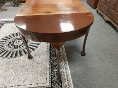 A mahogany demi-lune foldover top table on claw and ball feet, width 107 cm.