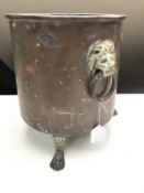 An antique copper coal bucket with lion mask handles on paw feet