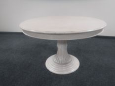 A contemporary circular pedestal extending table in a washed pine finish