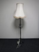 A wrought iron standard lamp with shade
