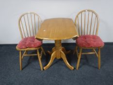 A drop leaf kitchen table and two rail backed chairs