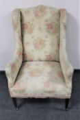 An Edwardian wingback armchair upholstered in a floral tapestry fabric