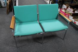 A mid twentieth century metal framed teak armed two seater settee upholstered in a turquoise fabric