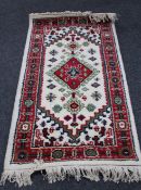 A fringed Indian woollen rug of geometric design on cream ground,