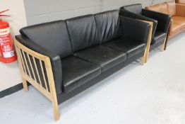A late 20th century Danish wood framed three seater settee and armchair with black leather cushions