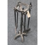 An antique three piece cast iron companion set on stand together with a coal shovel