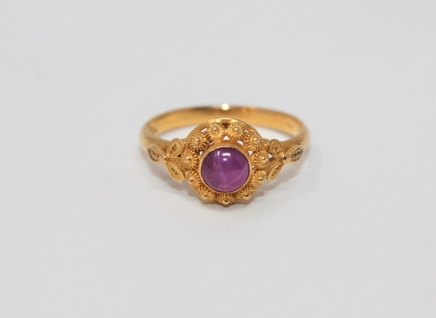 A cabochon chatoyant ruby ring set in high carat yellow gold, size M, indistinctly stamped '23'.