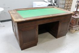 An early 20th century oak twin pedestal writing desk with slide top and a baize panel