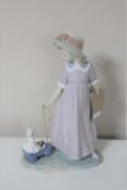 A Lladro figure of a girl pulling a doll in trolley
